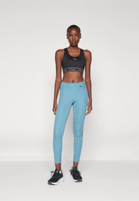 Puma KEEPS BRA - Športni modrček s srednjo podporo - black