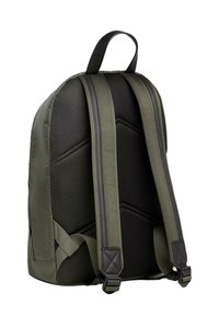 Zaino verde oliva con uno schienale in rete nera testurizzata, spallacci imbottiti e una maniglia superiore per il trasporto. Presenta dettagli di cuciture diagonali.