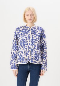 Floral patterned jacket in cream with blue flowers, featuring a round collar, long sleeves, and front pockets outlined in blue piping.
