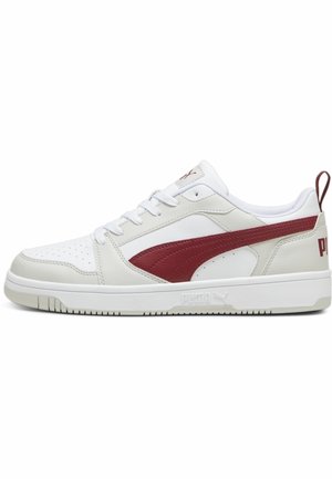 Biały niski sneaker z czerwonym paskiem z logo Puma, białymi sznurówkami, teksturowaną podeszwą i bordowym uchwytem na pięcie, pokazany z boku na jednolitym tle.