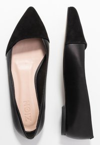 Ballerines noires à bout pointu avec un avant en suède et des côtés en cuir lisse. L'intérieur dispose d'une semelle intérieure texturée et légère avec un logo en relief. Talon bas.