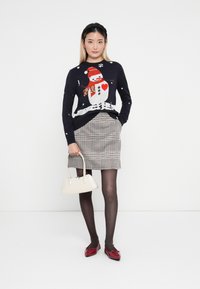 Navy sweater with white snowman design; gray houndstooth skirt; black tights; red patent shoes; white handbag with a rounded shape.