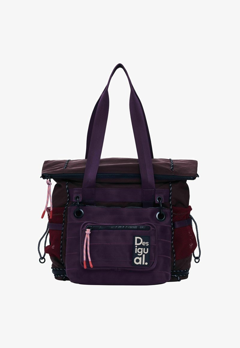 Lilla tote-taske med en rulle-top design, flere ydre lommer, netpaneler på siderne og kontrasterende hardware-detaljer.