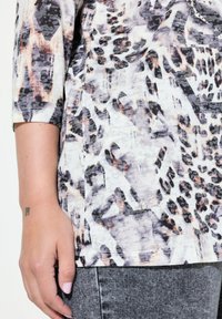 Multicolore top met een luipaardprintpatroon in tinten van zwart, grijs en perzik, met een zachte stoftextuur en driekwart mouwen.
