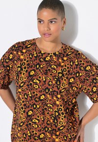 Bruine blouse met korte mouwen met een gedurfd zwart en geel dierenprint ontwerp, met een ontspannen pasvorm en zachte stoftextuur.