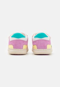 Baskets multicolores avec un dessus en suède rose, des accents blancs, des détails turquoise et jaunes, et une semelle beige texturée.