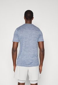 Μπλε κοντομάνικο T-shirt με ρίγα, με στρογγυλή λαιμόκοψη, εμφανιζόμενο από πίσω. Το ύφασμα έχει λεία υφή και λεπτές διακυμάνσεις στο χρώμα.