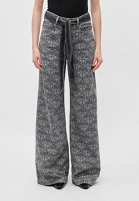 Wide-leg jeans in patterned gray denim with a belted waist. Features front pockets and a textured design, complemented by a smooth finish.