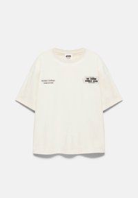 T-shirt blanc à manches courtes Star Wars avec les inscriptions « The Empire Strikes Back » et « The saga continues in your galaxy soon » imprimées sur l'avant.