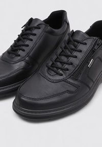 Chaussures en cuir noir avec un design à lacets et une fermeture éclair latérale, texture lisse, bout arrondi et détails de couture subtils.