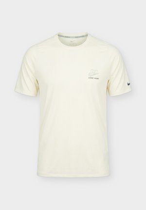 Natúr fehér Nike rövid ujjú futó póló, amelyen kis "NIKE DISTANT DREAMS" felirat és logó található a mellkason, valamint Swoosh a bal ujján.