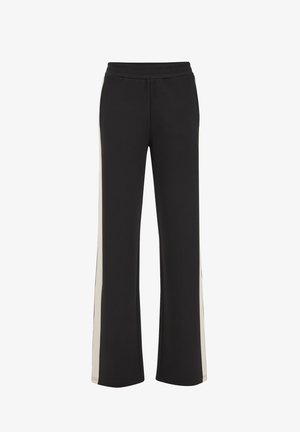 Fekete sportnadrág laza szabással, széles lábmegoldással és krémszínű oldalcsíkokkal. Puha, rugalmas anyagból készült.