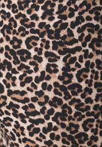 Leopard print fabric in beige and black, featuring varying size spots against a light background, with a soft, textured surface.