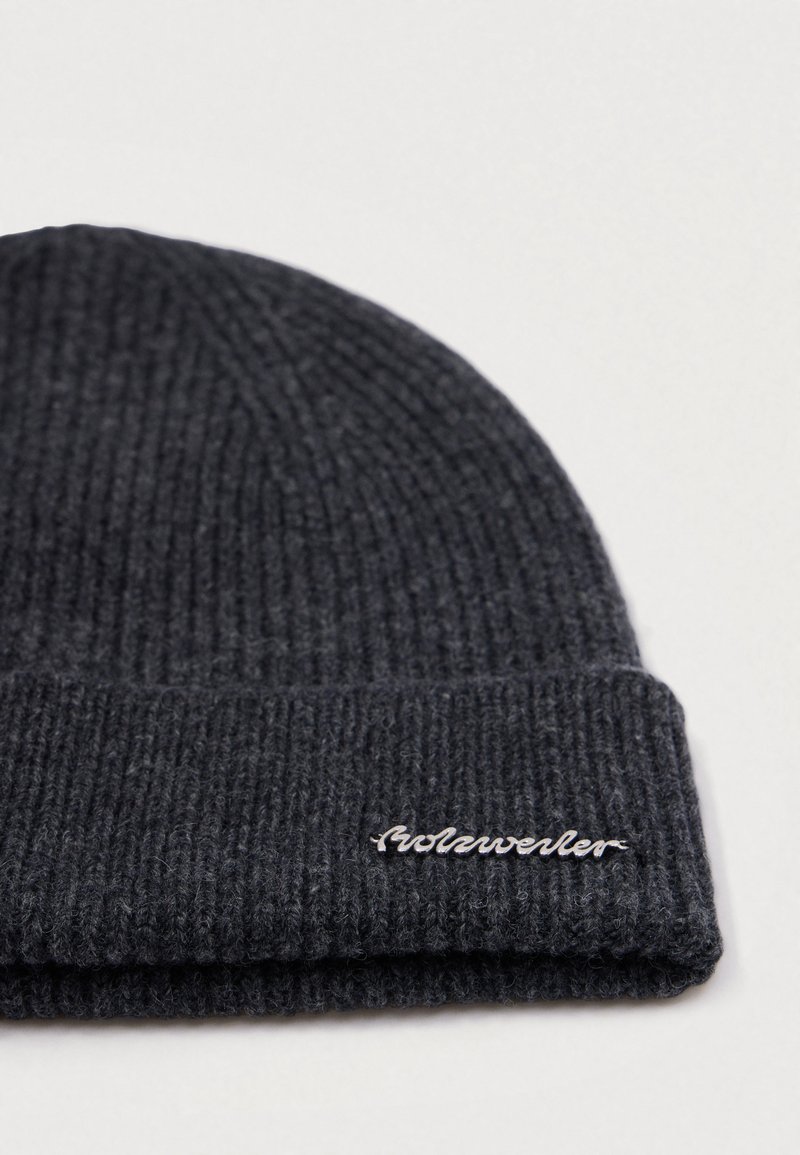 Dunkelgraue ribbelige Strickmütze mit umgeschlagenem Rand und kleinem metallic Markenlogo-Detail am Bündchen.