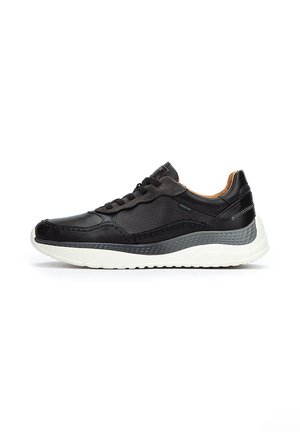 Zapatilla negra con un diseño texturizado, que presenta paneles de cuero liso y malla. Suela blanca con detalles en gris y suturas sutiles.