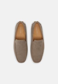Grå mockasko i slip-on modell med rund tå, kontrasterande sömmar och mjuk lädersula. Har en minimalistisk design utan synlig hårdvara.