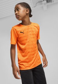 Dzidri spīdīgas oranžas sporta krekls ar īsām piedurknēm, kuram ir melns Puma logo un smalkas horizontālas tekstūras uz auduma.