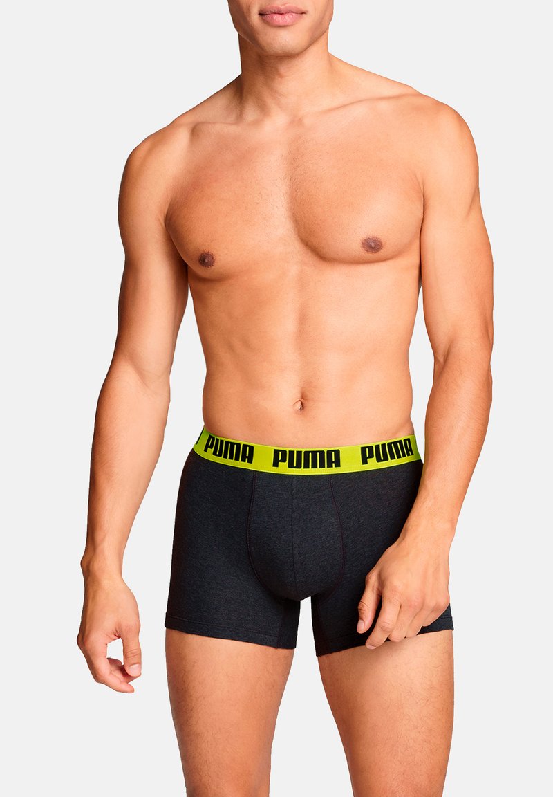 Schwarze Boxershorts aus Baumwolle mit einem auffälligen gelben Gummibund, auf dem das "PUMA"-Logo in Schwarz prangt. Glatte Textur, taillierte Passform.