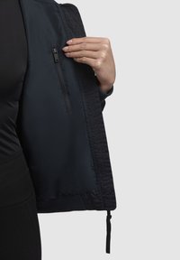 Giacca bomber nera con una finitura liscia e opaca, caratterizzata da una tasca con zip sul lato sinistro e polsini elasticizzati per una vestibilità sicura.