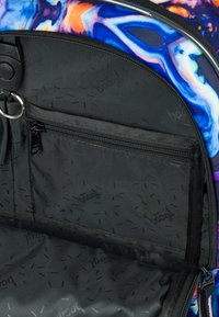 Interno dello zaino caratterizzato da un rivestimento in tessuto nero con una tasca con zip. L'esterno presenta vivaci motivi astratti multicolori.