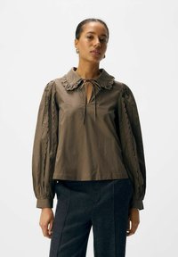 Braune Bluse aus Baumwollmischung mit rüschigem Kragen, Bindedetail und gewellten Stickereien an den Ballonärmeln; lockere Passform.