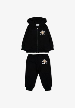 Czarny dres dla malucha z bluza na suwak i spodniami, z motywem twarzy misia oraz rozproszonym napisem "Moschino" na obu elementach.