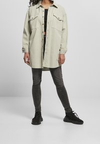 Ljusgrön oversized skjorta med knappar och två bröstfickor, tillsammans med svarta tajta jeans och svarta sneakers. Slät tygkvalitet, avslappnad passform.