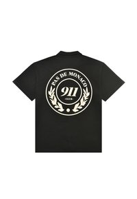 Svart skjorte med korte ermer og en hvit sirkel med logo på baksiden som sier "PAS DE MONACO 911 CLUB" omgitt av laurbærblader.