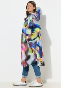 Abrigo largo colorido con capucha, que presenta una mezcla de patrones abstractos en azul, rosa y amarillo; hecho de un material ligero y resistente al agua.