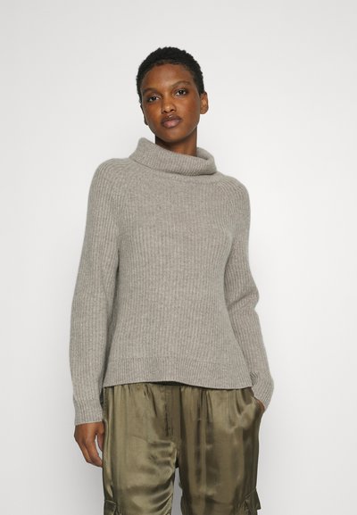 Light gray knitted sweater with a wide cowl neck, ribbed texture, and long sleeves, paired with olive green satin pants.