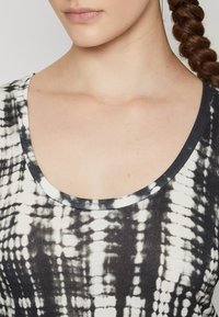 Black and white tie-dye T-shirt with a scoop neckline, made of soft fabric, featuring a textured pattern and a contrasting dark trim.
