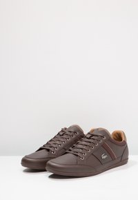 Bruna lädersneakers med mörkbruna accenter, rund tå, snörningsdesign och en logotyp på sidan. Mjuk beige foder. Platt gummisula.