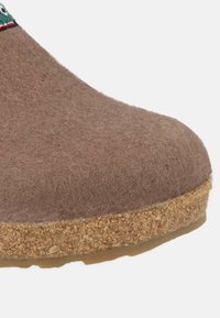 Pantofole di feltro marroni con punta arrotondata, soletta in sughero e suola in gomma. Presenta una fascia decorativa verde e rossa vicino all'apertura.