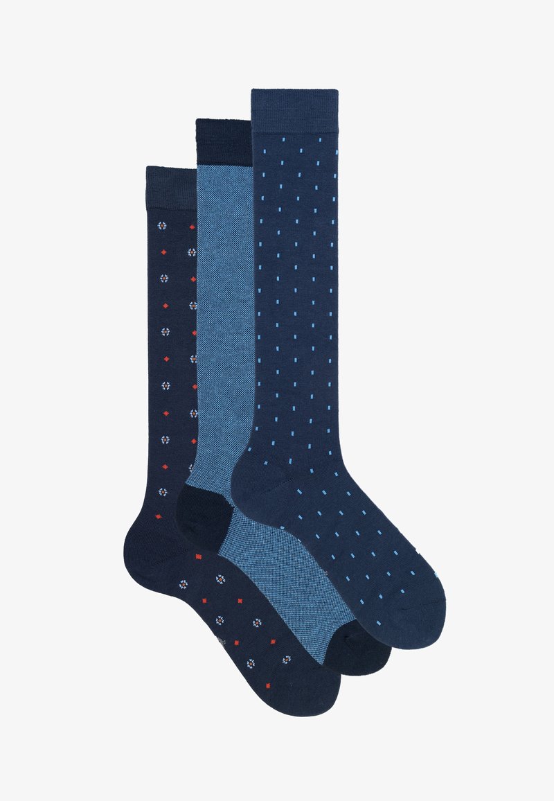 Tre paia di calzini al ginocchio: uno blu scuro con motivi rossi e bianchi, uno azzurro uniforme e uno blu scuro con pois azzurri.