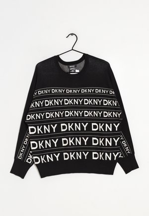 Czarny sweter z okrągłym dekoltem z białymi, powtarzającymi się paskami z logo "DKNY" na przodzie, rękawach i klatce piersiowej, wiszący na czarnym wieszaku.