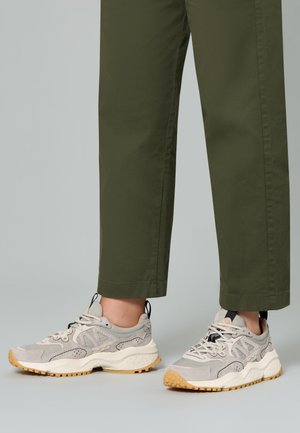 Sneaker grigie chiare con pannelli in suede e rete testurizzati, suola intermedia bianca e suola in gomma. Abbinati a pantaloni verde oliva. Lacci neri.