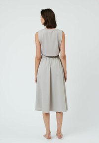 Robe sans manches, longueur genou en tissu gris clair, avec une taille froncée et une jupe fluide. Texture lisse avec un élastique à la taille.