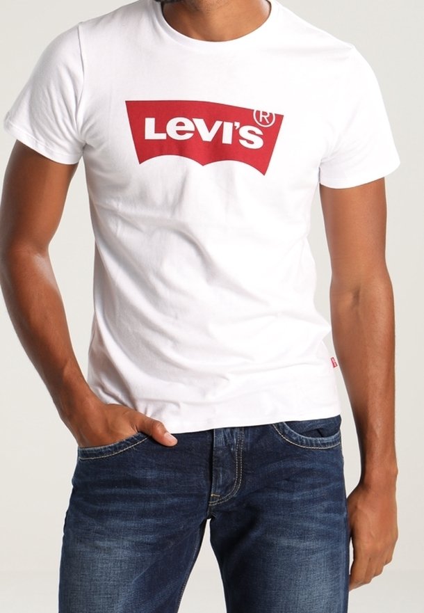 T-shirt en coton blanc avec un logo Levi's rouge sur la poitrine; accompagné de jeans en denim bleu, avec des coutures et des poches visibles.