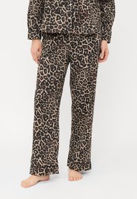 Pysjamasett med leopardmønster i myk stoff. Inkluderer en knapp-up skjorte og løs-passende bukser, med en brettet mansjett ved kanten.