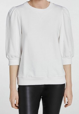 Witte blouse met opgepofte driekwartsmouwen en geribde manchetten gecombineerd met zwarte aansluitende broek.