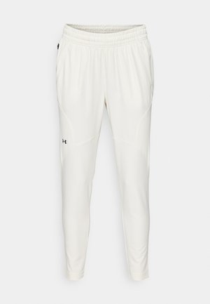 Lightweight, cream-colored athletic pants with an elastic waistband, tapered fit, side pockets, and a small black logo on the left leg.