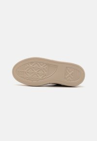 Semelle de chaussure au design plat, fabriquée en caoutchouc beige texturé. Comprend un motif en losange et un détail de marque au centre.