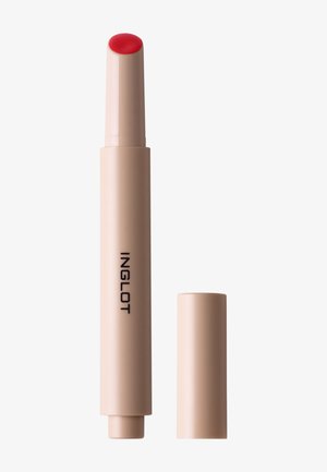 Baume à lèvres cylindrique beige avec embout rouge et bouchon retiré, étiqueté "INGLOT" sur le côté, sur fond blanc.