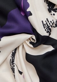 Tessuto di seta attorcigliato, con un motivo floreale in viola, nero e crema. Texture liscia con zone chiare e scure in contrasto.