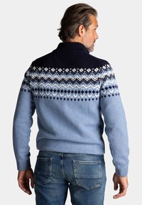 Gebreide trui met een hoge kraag, een blauwe ombre-ontwerp en ingewikkelde patronen in marineblauw en wit over de schouders en de rug.