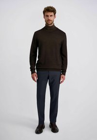 Bruine turtleneck trui gecombineerd met donkergrijze broek. De outfit heeft stevige texturen en een getailleerd ontwerp met lange mouwen en een geribbelde zoom.