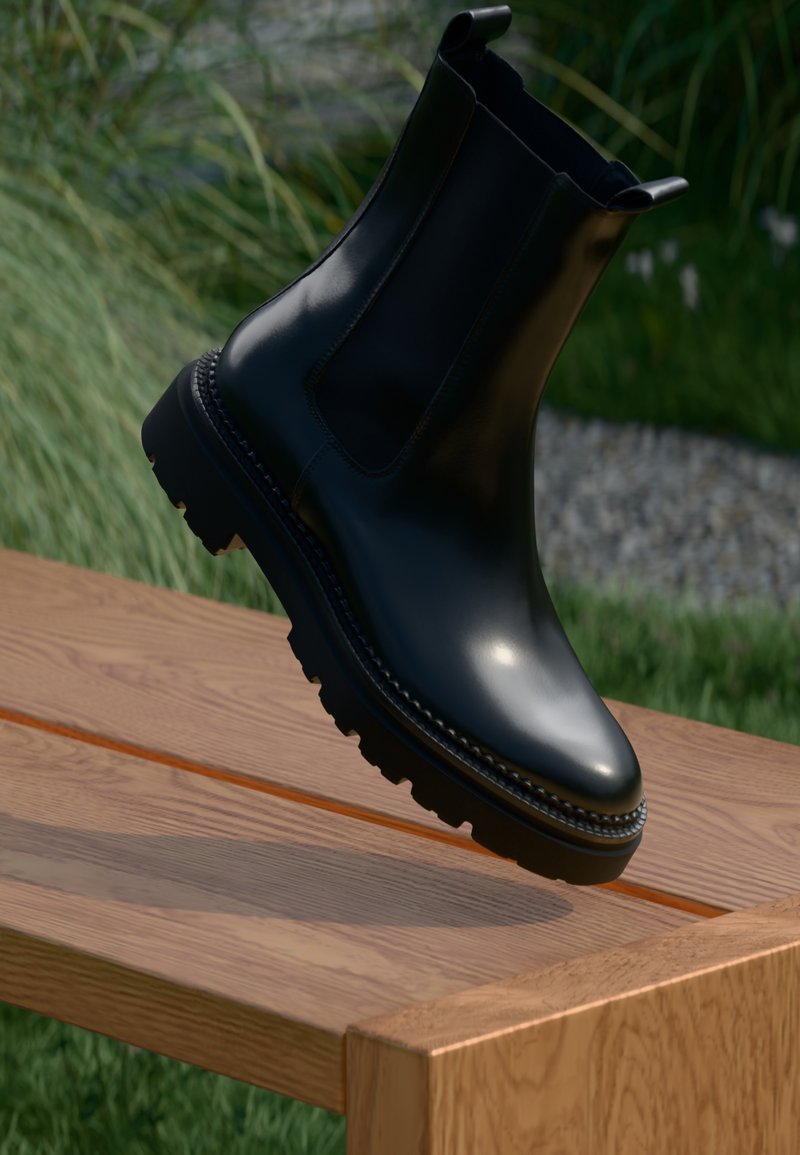 Cizme negre din piele până la gleznă cu un finisaj lucios, vârf rotunjit, panouri laterale elastice și o talpă masivă cu caneluri adânci pentru aderență.