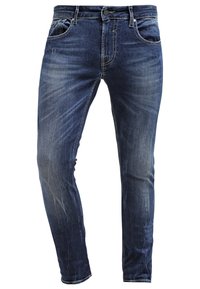 Jeans de mezclilla azul oscuro con corte ajustado, que presentan un diseño clásico de cinco bolsillos, un ligero desgaste y costuras en contraste.