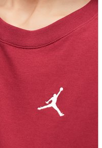 Κόκκινο βαμβακερό φούτερ με στρογγυλή λαιμόκοψη και λευκό λογότυπο Jumpman κεντημένο στο στήθος. Λείο ύφασμα, μινιμαλιστικός σχεδιασμός.