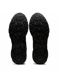 Schwarze Gummisohlen mit tiefen, robusten Profilen und geometrischen Mustern, entwickelt für Grip und Langlebigkeit.